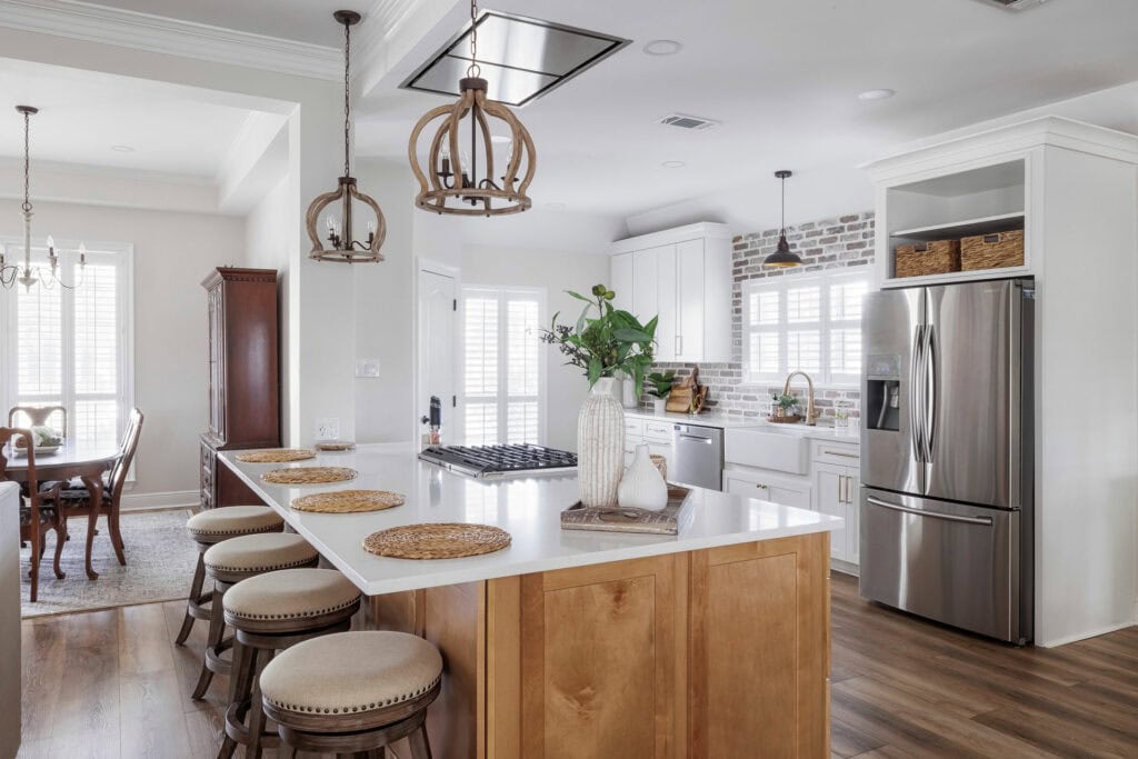 Kitchen with large island, bar seating, white cabinetry, and exposed brick backsplash