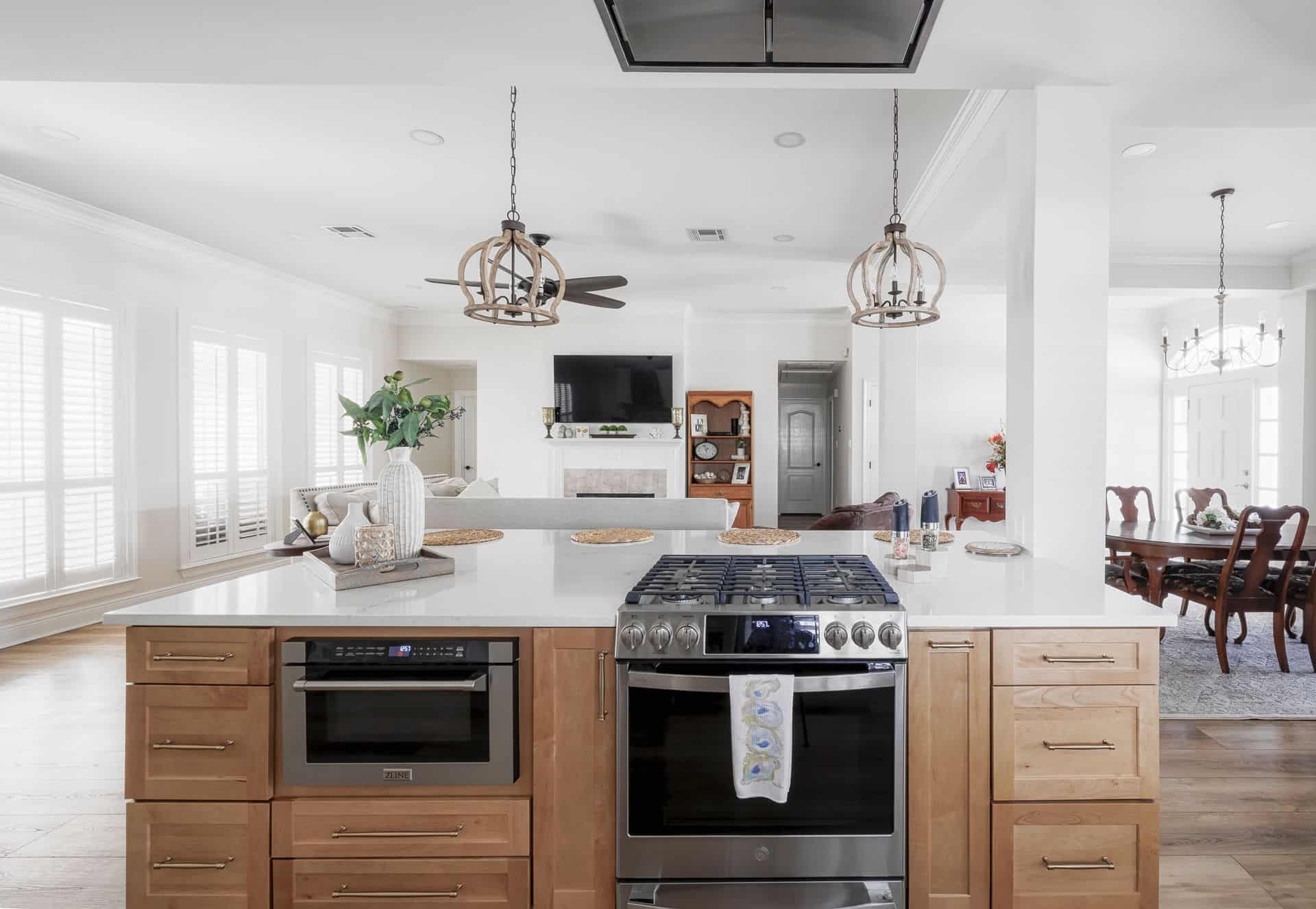 Kitchen island with built-in range and microwave, pendant lights, and open living area