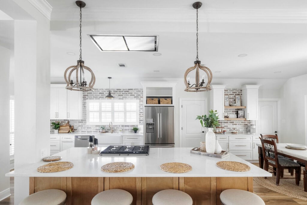 White and wood kitchen with brick backsplash, pendant lighting, and central island