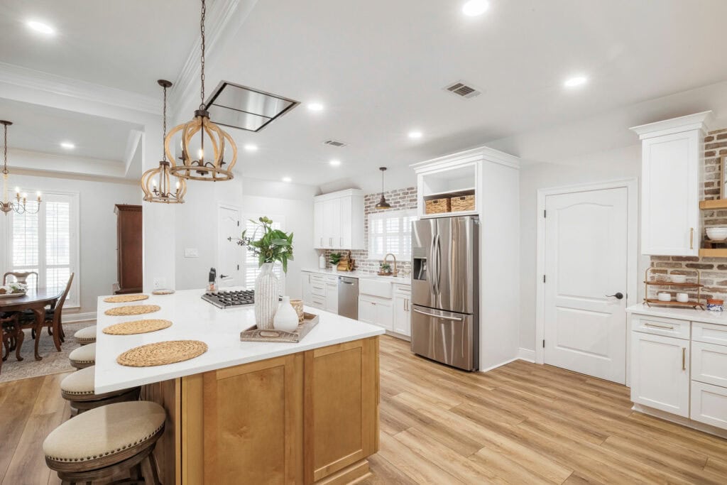 Open kitchen with large island, white cabinetry, stainless steel appliances, and wood floors