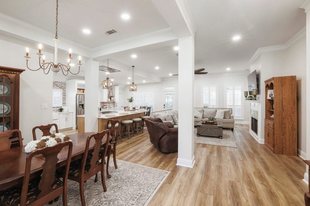Open-concept kitchen, dining, and living area featuring wood flooring, recessed lighting, custom island with seating, and cohesive transitional design.