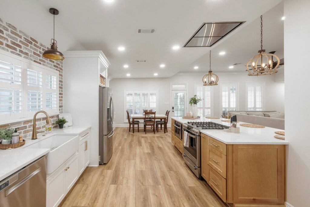 Modern kitchen with farmhouse sink, wood floors, brick backsplash, and open layout