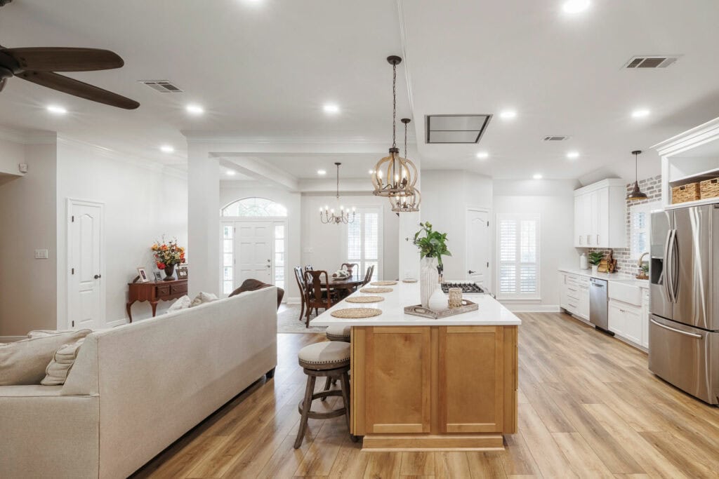 Open-concept kitchen and living area with natural light, wood floors, and farmhouse-inspired finishes
