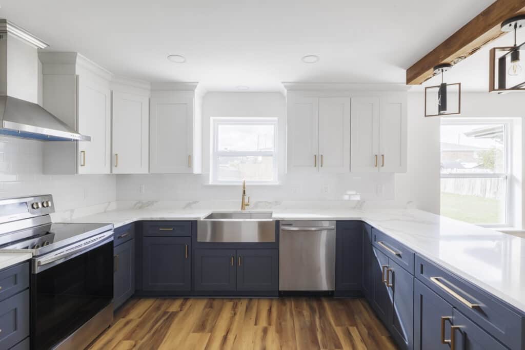 Modern two-tone kitchen with shaker cabinets, farmhouse sink, and quartz countertops