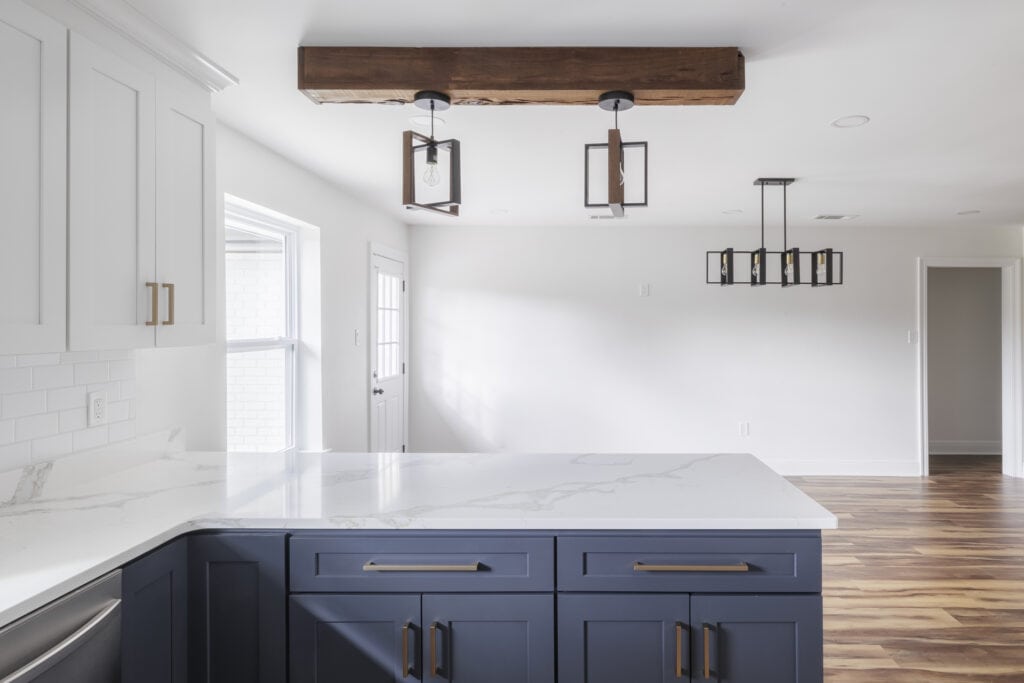 Close-up of navy kitchen island with quartz countertop and exposed beam lighting feature