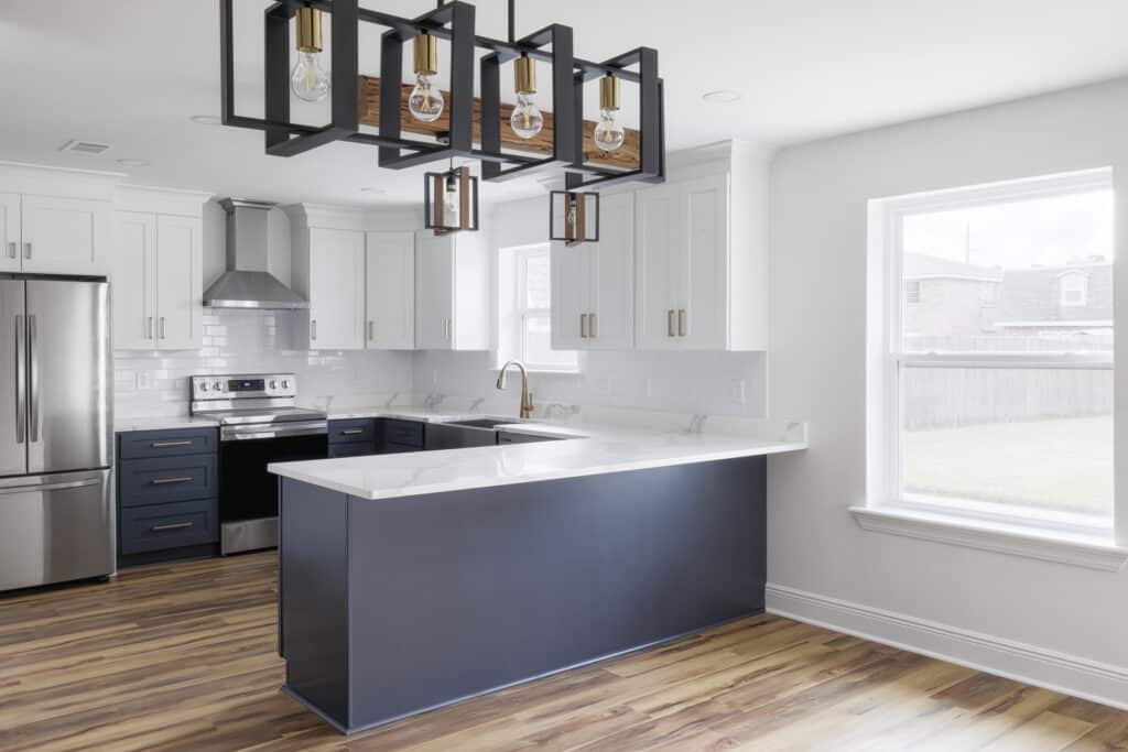 Modern kitchen remodel with two-tone cabinets, stainless appliances, and waterfall-edge quartz island.