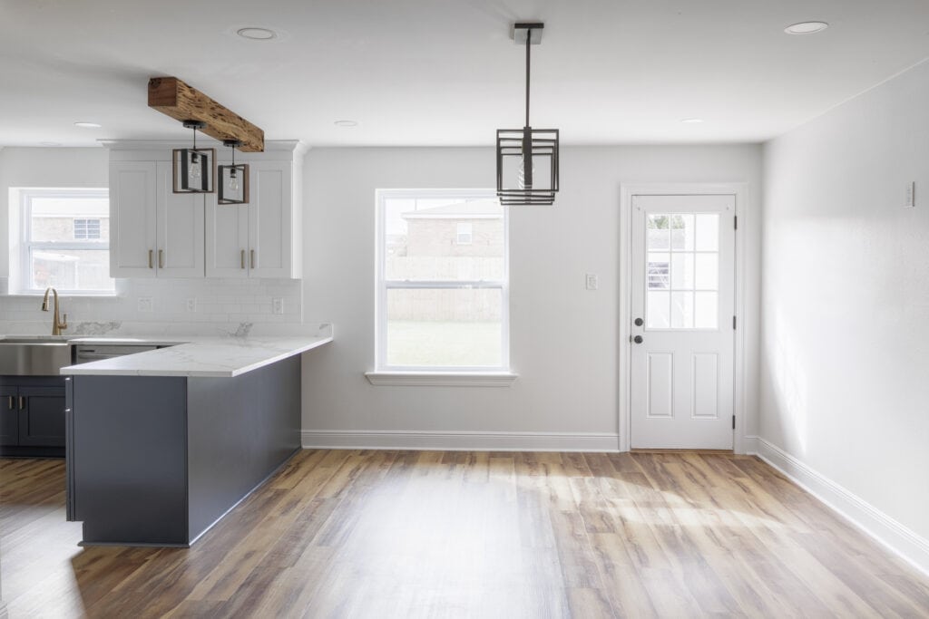 Bright open dining area with natural light and modern pendant lighting adjacent to a two-tone kitchen