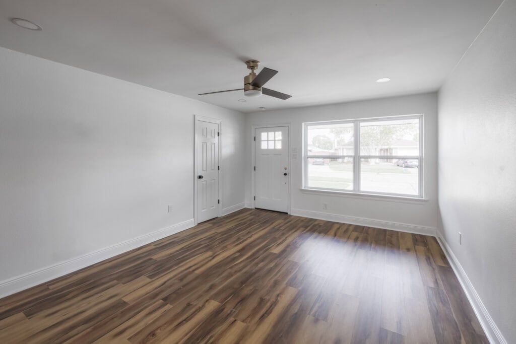 Bright entryway and living space with large front window, white walls, and wood-look flooring.