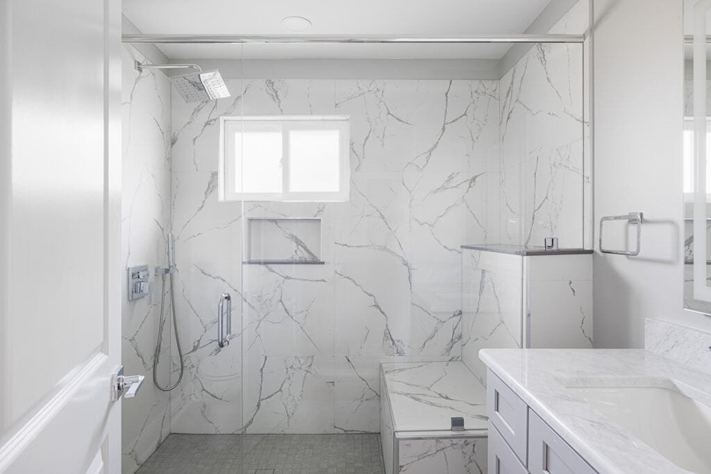 Modern bathroom renovation with a marble-look shower, light gray vanity, and clean white finishes in the Hester project.
