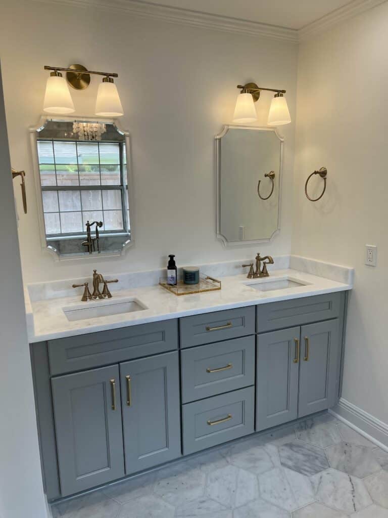 Elegant double vanity with marble countertop, brass fixtures, and custom cabinetry in a remodeled bathroom.