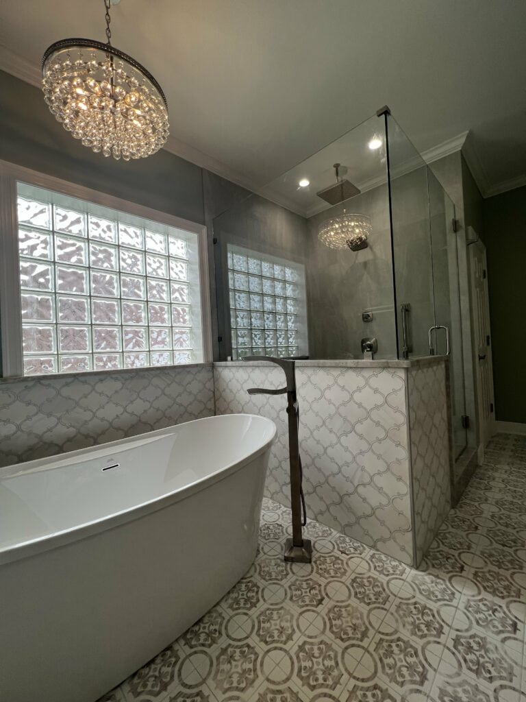 Elegant master bathroom remodel featuring a freestanding tub, glass shower enclosure, and intricate patterned tile floors.