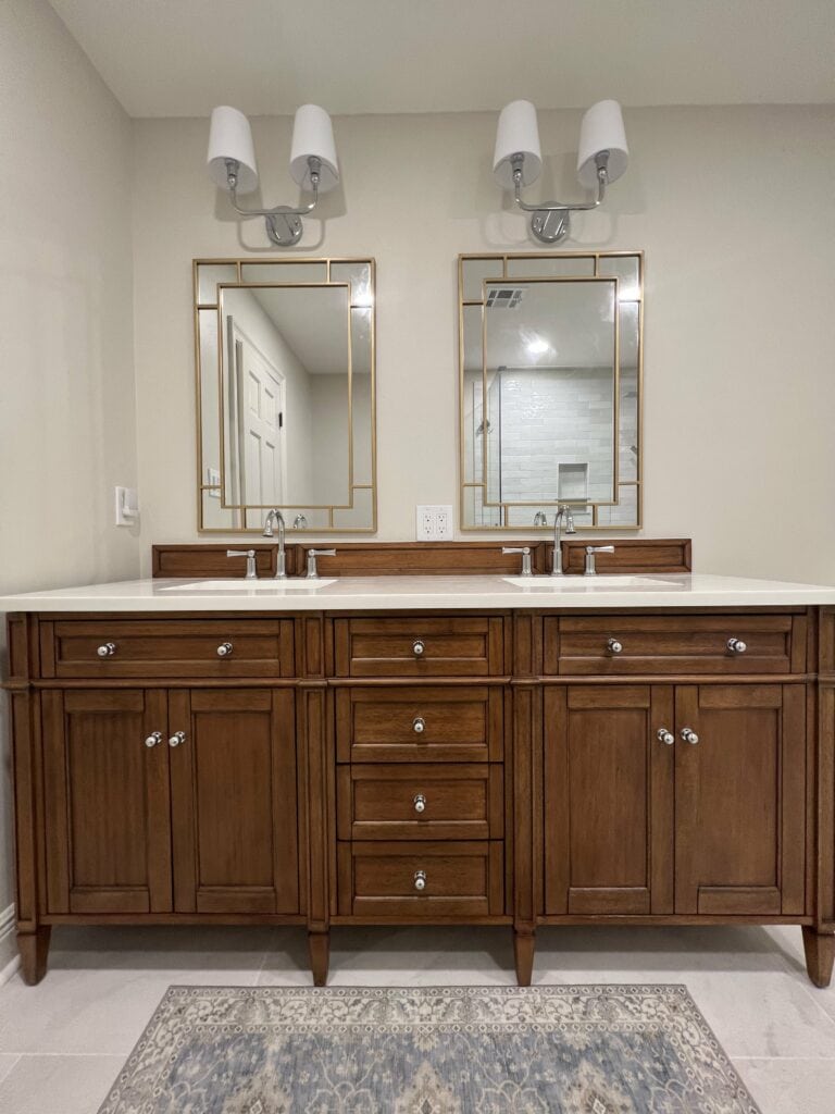 Double vanity with rich wood cabinetry, quartz countertops, and framed mirrors