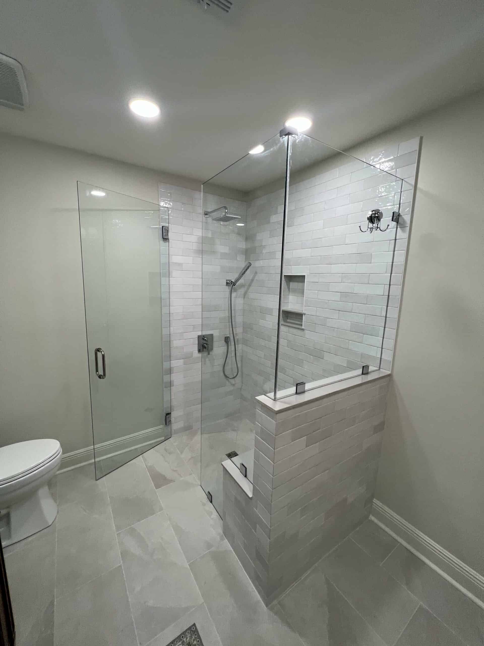Curbless walk-in shower with glass enclosure and subway tile walls
