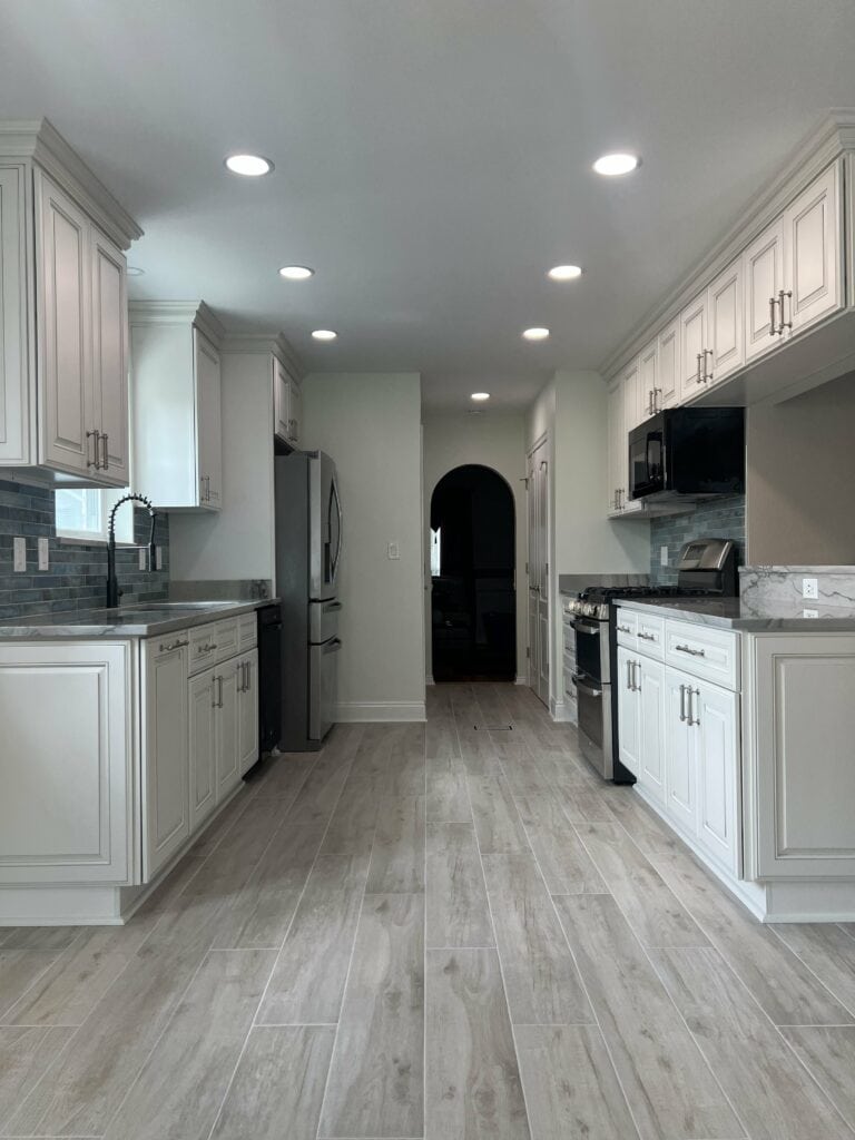 Close-up of quartzite countertops with seamless veining, new custom cabinetry, and undercabinet lighting in a Destrehan kitchen renovation.