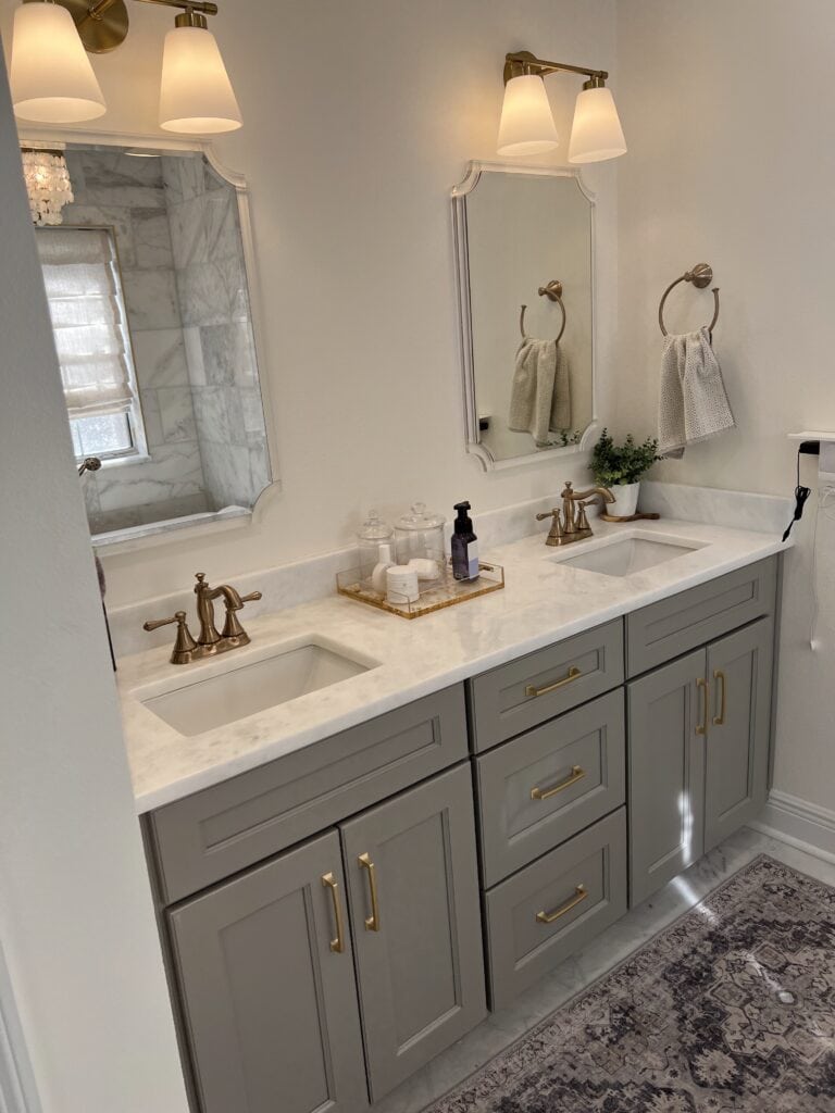 Double vanity with brass hardware and quartz countertop in luxury bathroom.