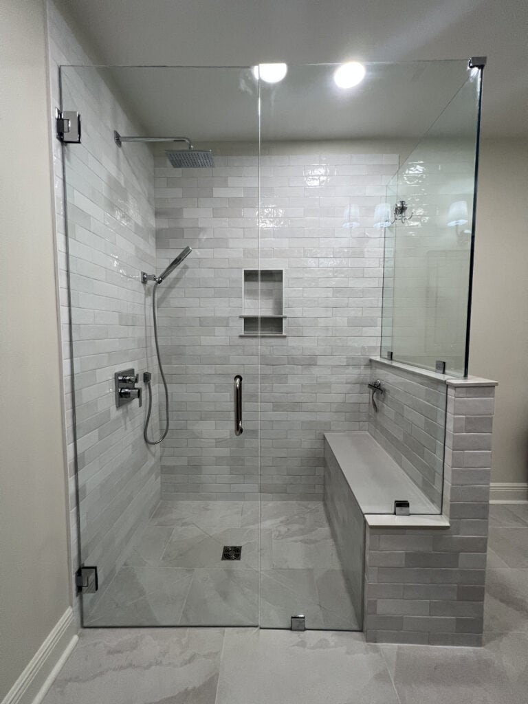 Frameless glass shower with built-in bench and polished subway tile walls