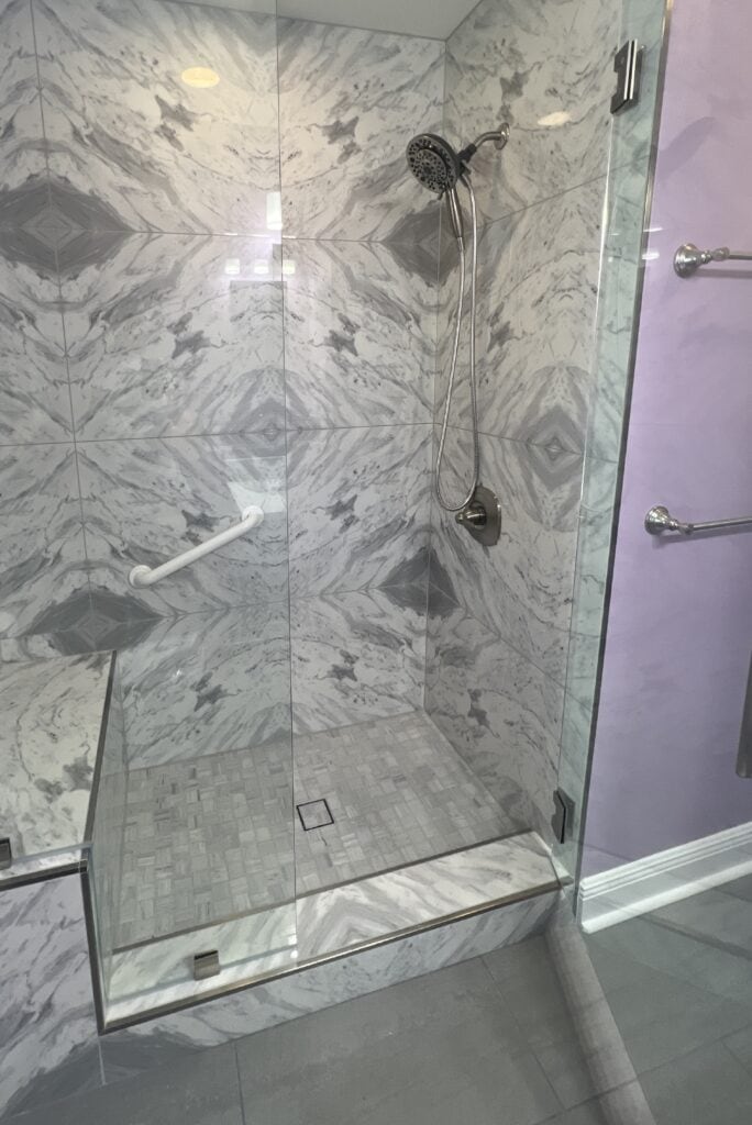 Close-up view of a custom shower pan with integrated tile-matched drain cover in a luxury bathroom remodel.